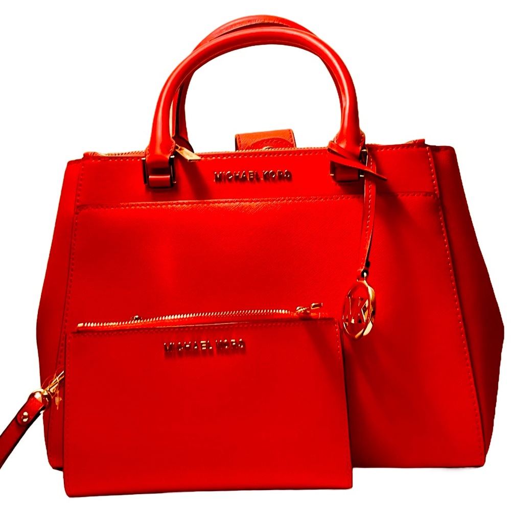 A  coral leather Micheal Kors satchel purse and wallet as a traveling set.